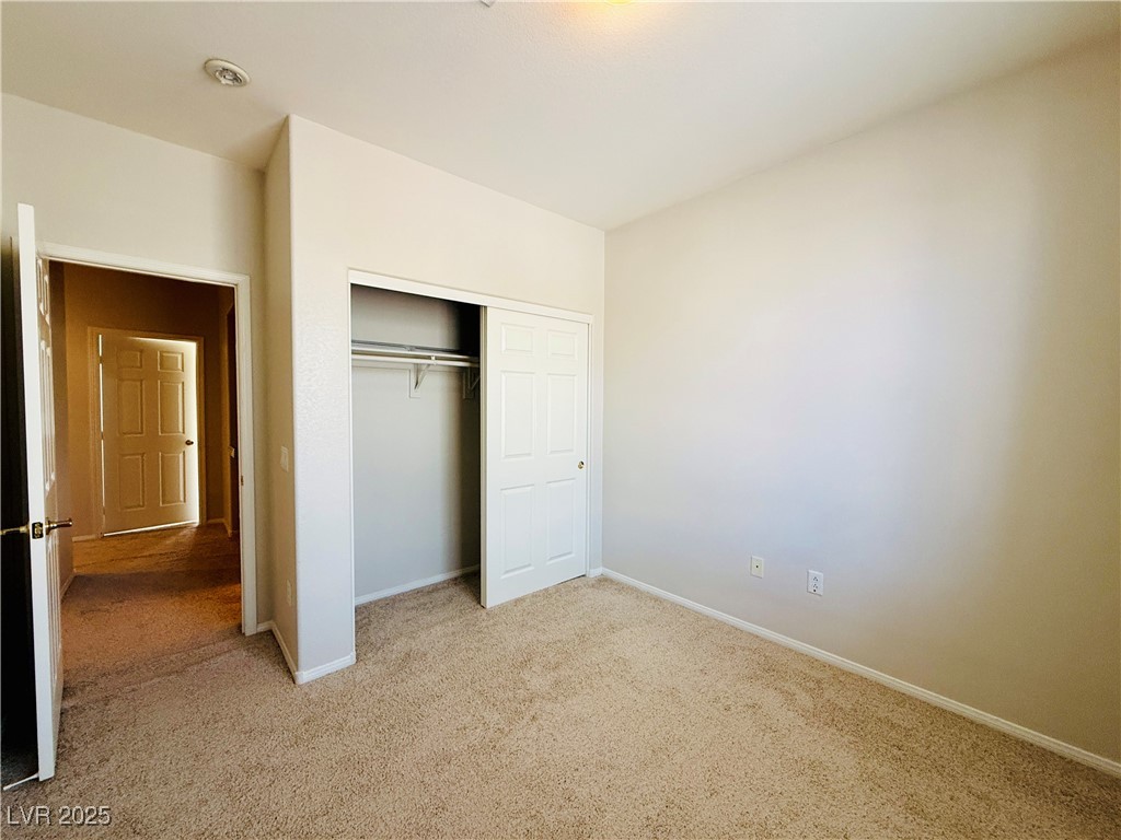 10231 Deerfield Beach Avenue, Unit 103 Las Vegas, NV 89129 - Photo 18 of 31 Unfurnished bedroom featuring light colored carpet and a closet