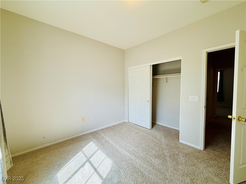 10231 Deerfield Beach Avenue, Unit 103 Las Vegas, NV 89129 - Photo 21 of 31 Unfurnished bedroom with light carpet and a closet