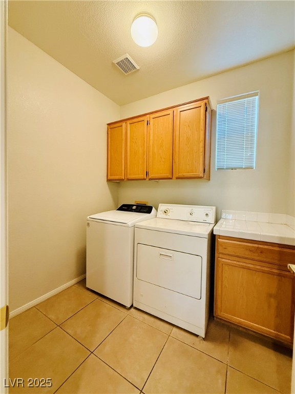 10231 Deerfield Beach Avenue, Unit 103 Las Vegas, NV 89129 - Photo 25 of 31 Laundry area featuring cabinet space, light tile patterned floors, separate washer and dryer, and a textured ceiling