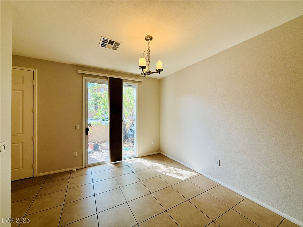 10231 Deerfield Beach Avenue, Unit 103 Las Vegas, NV 89129 - Photo 7 of 31 Spare room featuring light tile patterned floors and a chandelier