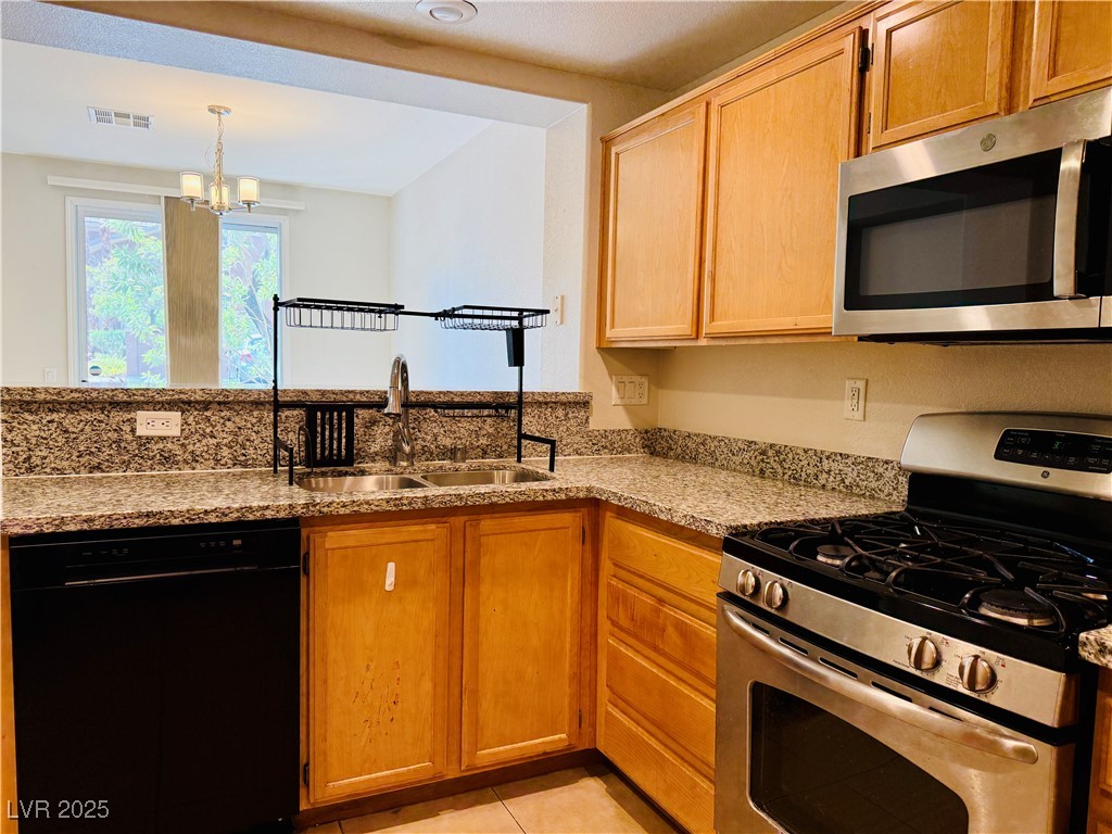 10231 Deerfield Beach Avenue, Unit 103 Las Vegas, NV 89129 - Photo 9 of 31 Kitchen with stainless steel appliances, light stone countertops, light tile patterned floors, a peninsula, and a chandelier