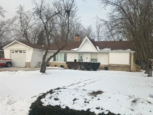 a front view of a house with a yard covered in snow
