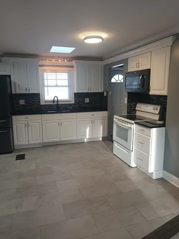 a large kitchen with stainless steel appliances granite countertop a stove and a sink