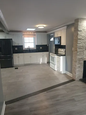 a view of kitchen with stainless steel appliances cabinets and a window
