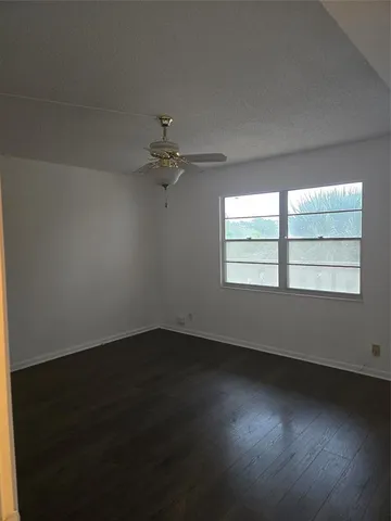 an empty room with wooden floor cabinet and windows