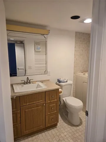 a bathroom with a granite countertop sink toilet and mirror