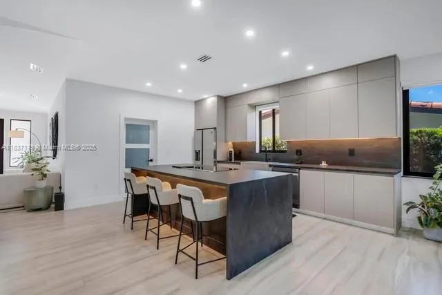 a kitchen with stainless steel appliances kitchen island granite countertop a table chairs sink and cabinets