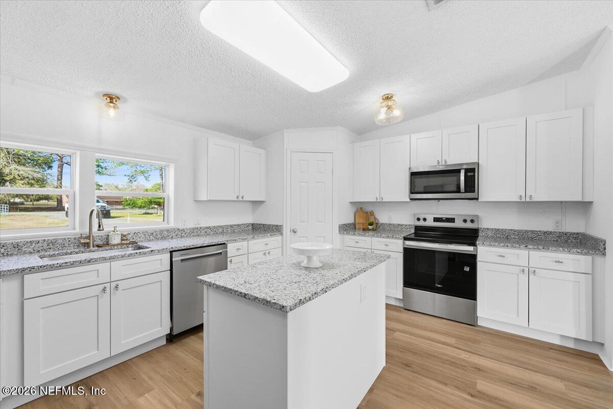 345 Jones Road Jacksonville, FL 32220 - Photo 17 of 32 a kitchen with stainless steel appliances granite countertop a sink stove cabinets and wooden floor