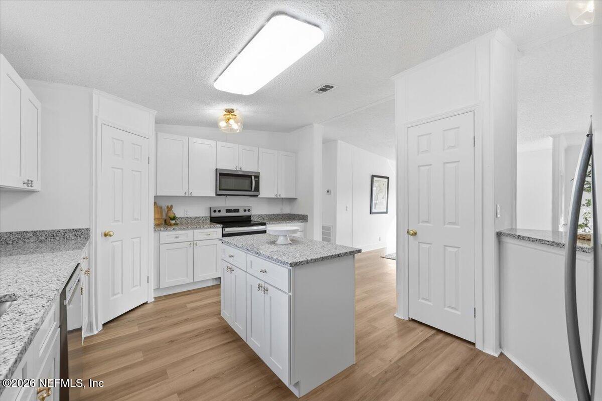 345 Jones Road Jacksonville, FL 32220 - Photo 18 of 32 a kitchen with stainless steel appliances a refrigerator a stove a sink and white cabinets