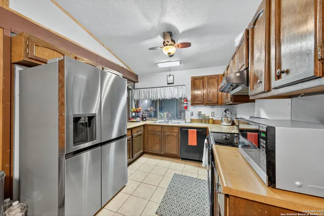 a kitchen with stainless steel appliances granite countertop a refrigerator a stove and a sink with cabinets