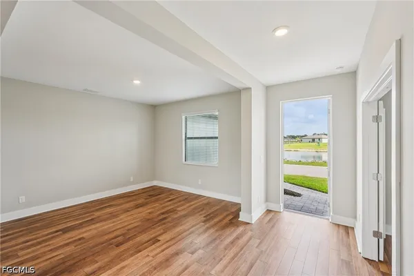 a view of an empty room with wooden floor and a window