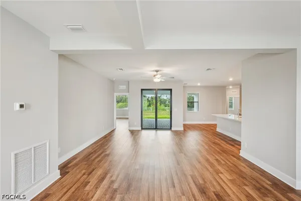 a view of empty room with wooden floor and fan