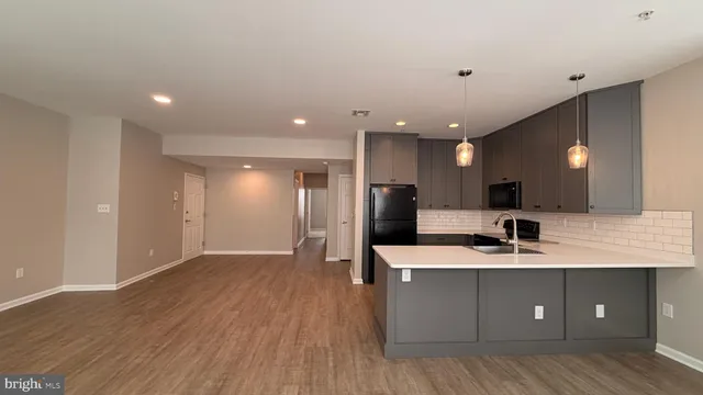 a large kitchen with a large counter top a sink stainless steel appliances and cabinets