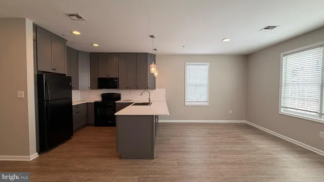 a kitchen with granite countertop a refrigerator a sink dishwasher and a stove with wooden floor