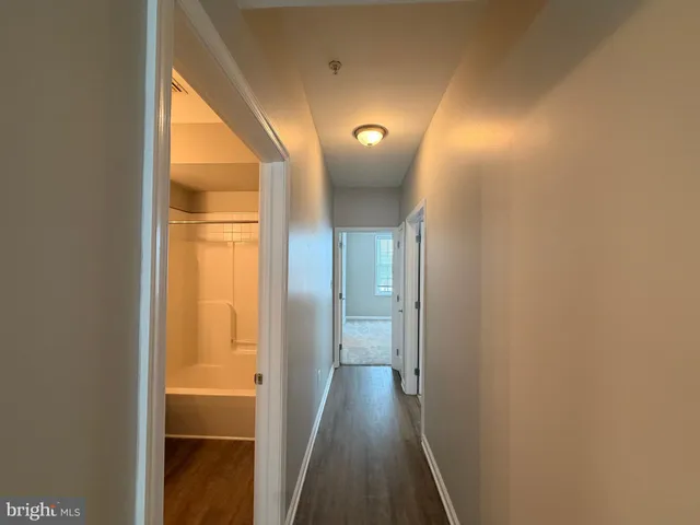 a view of a hallway with wooden floor and a bathroom
