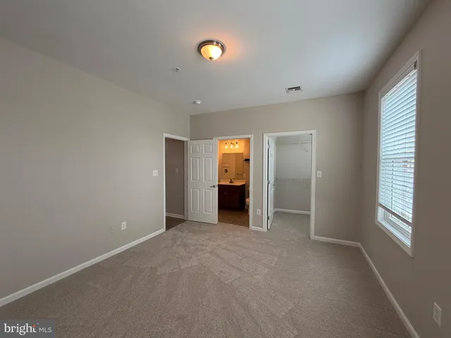 a view of an empty room with a window and bathroom