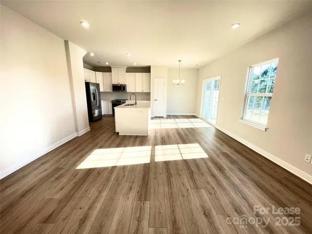 a living room with stainless steel appliances kitchen island granite countertop furniture and a wooden floor