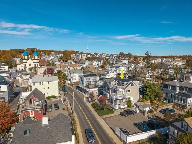 an aerial view of ocean and residential houses with outdoor space
