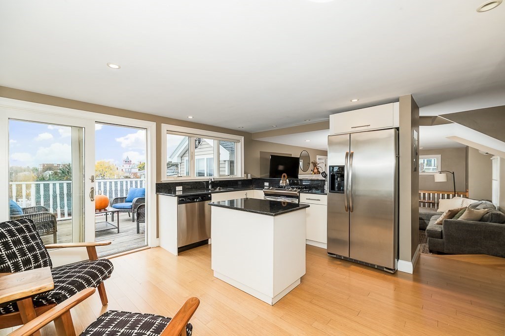 160 Prospect Street, Unit 3 Gloucester, MA 01930 - Photo 7 of 22 a kitchen with stainless steel appliances kitchen island granite countertop a refrigerator and a stove top oven