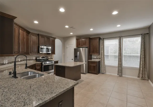 a kitchen with stainless steel appliances granite countertop a refrigerator stove microwave and sink