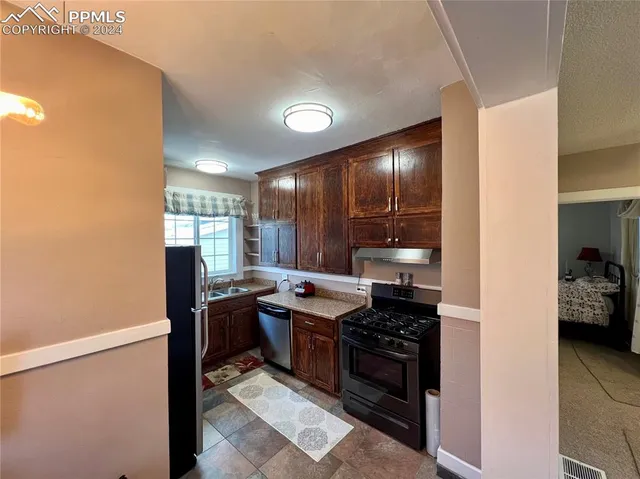 a kitchen with stainless steel appliances granite countertop a stove refrigerator and sink