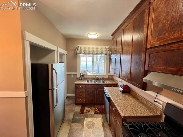 a kitchen with a refrigerator and wooden floor