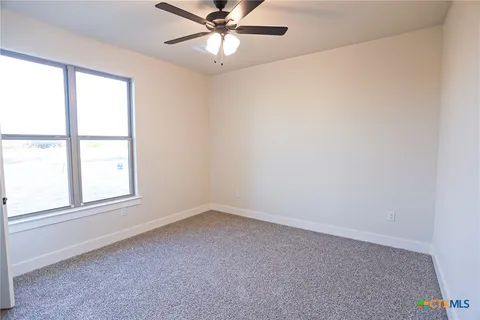 an empty room with a window and a fan