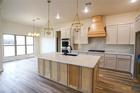 a kitchen with kitchen island a sink stove and wooden floor