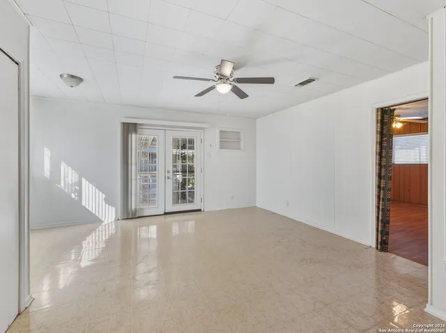 an empty room with chandelier fan and windows