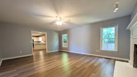an empty room with wooden floor fan and windows