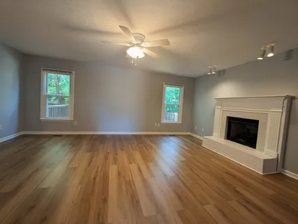 a kitchen with stainless steel appliances granite countertop a refrigerator a sink dishwasher a stove and white countertops with wooden floor