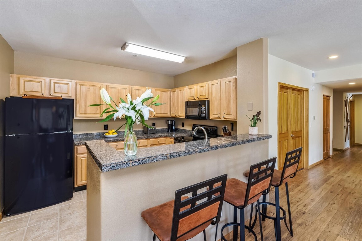 23110 Highway 6, Unit 5015 Keystone, CO 80435 - Photo 9 of 32 a kitchen with stainless steel appliances granite countertop a sink a stove a refrigerator cabinets and dining table