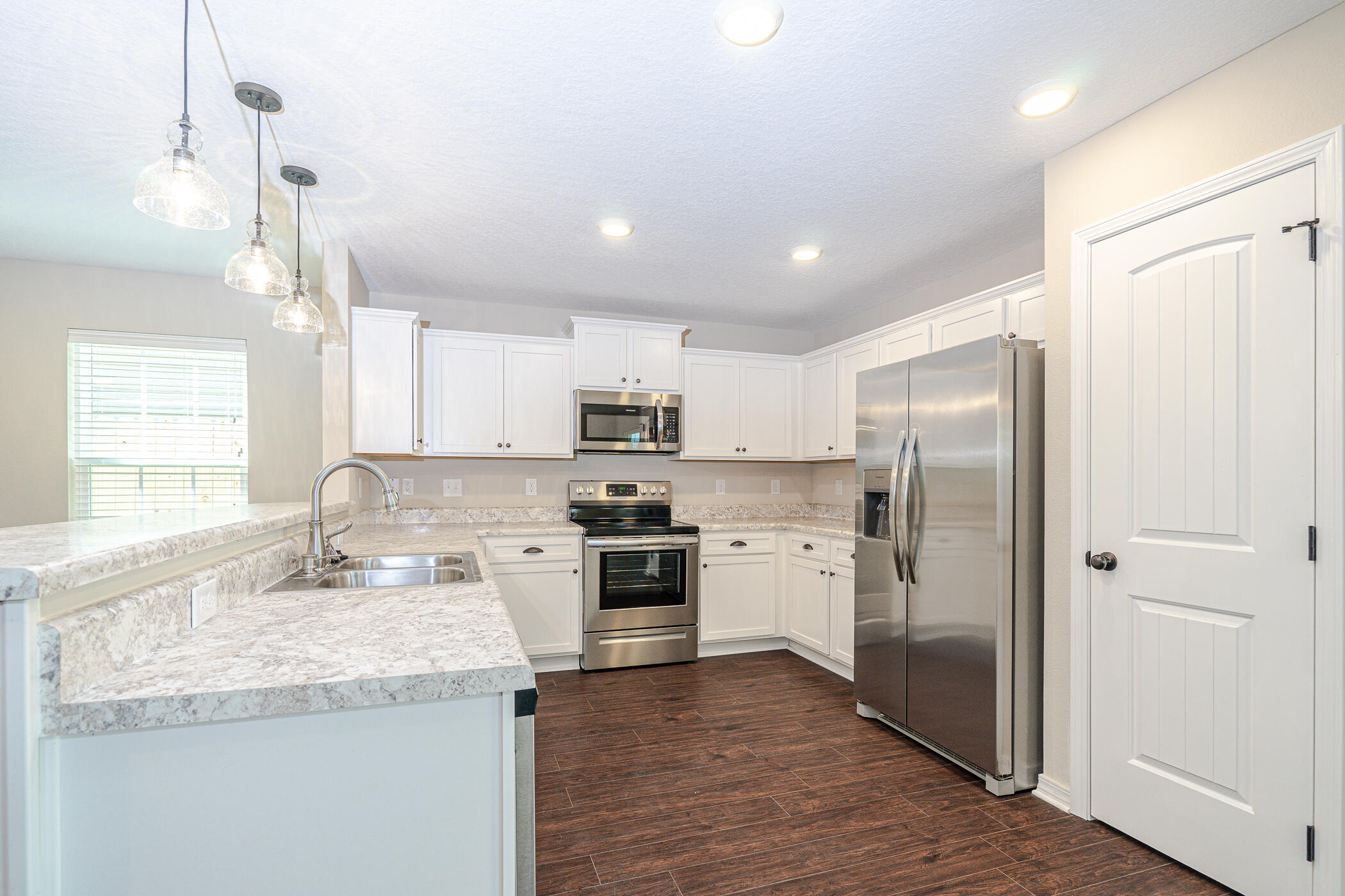 243 Wainwright Drive Crestview, FL 32539 - Photo 12 of 38 a kitchen with stainless steel appliances granite countertop a refrigerator a sink dishwasher a stove with white cabinets and wooden floor