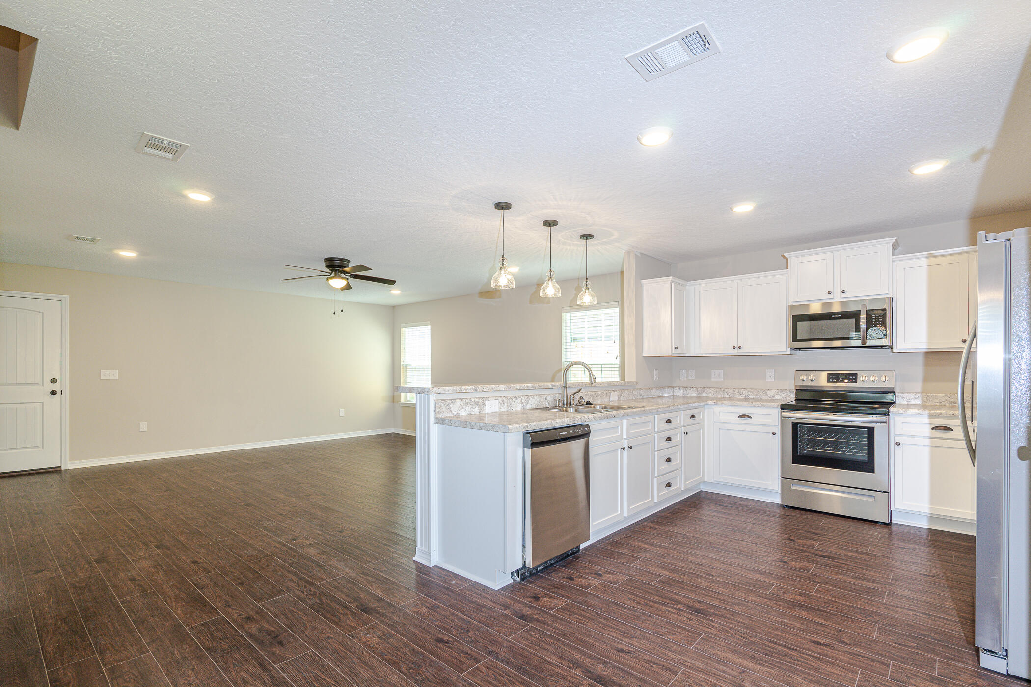 243 Wainwright Drive Crestview, FL 32539 - Photo 14 of 38 a large kitchen with stainless steel appliances granite countertop a stove top oven a sink a refrigerator and white cabinets with wooden floor