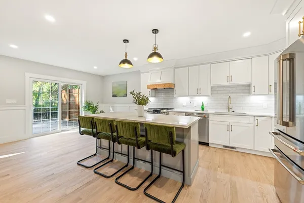 a kitchen with stainless steel appliances granite countertop a table chairs sink and cabinets