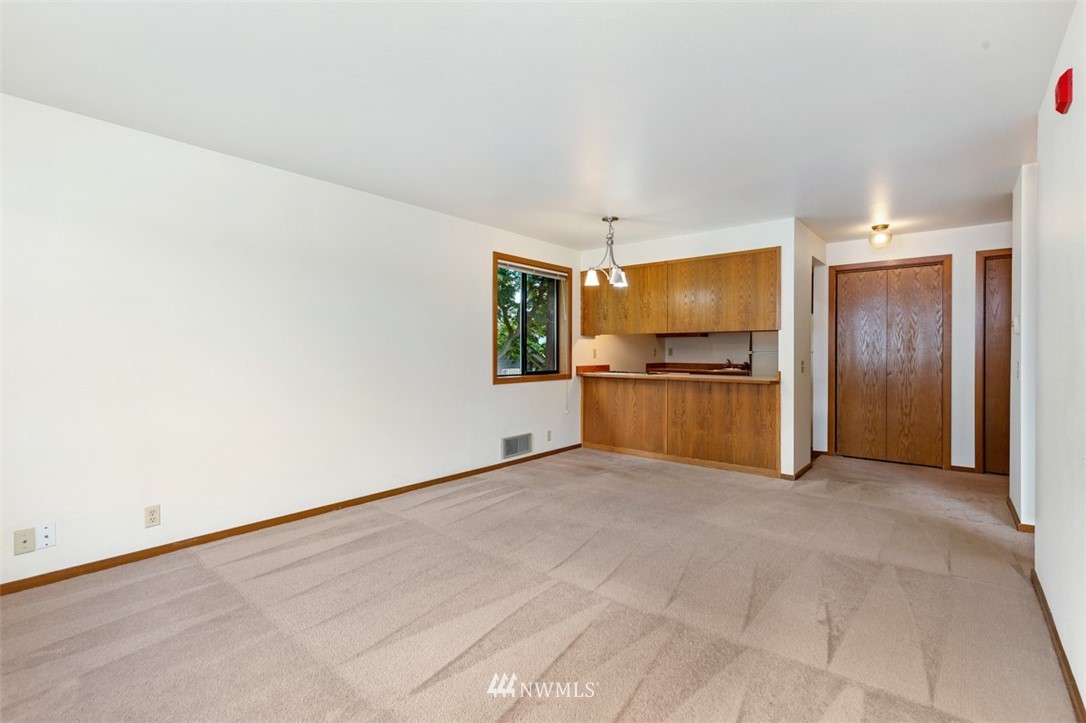 1300 North 107th Street Seattle, WA 98133 - Photo 11 of 20 an empty room with a kitchen and a refrigerator