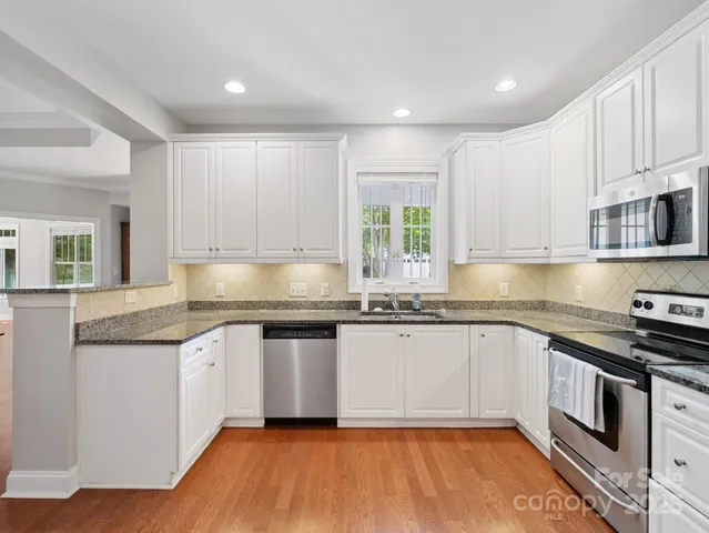 a kitchen with stainless steel appliances granite countertop a stove a sink and white cabinets