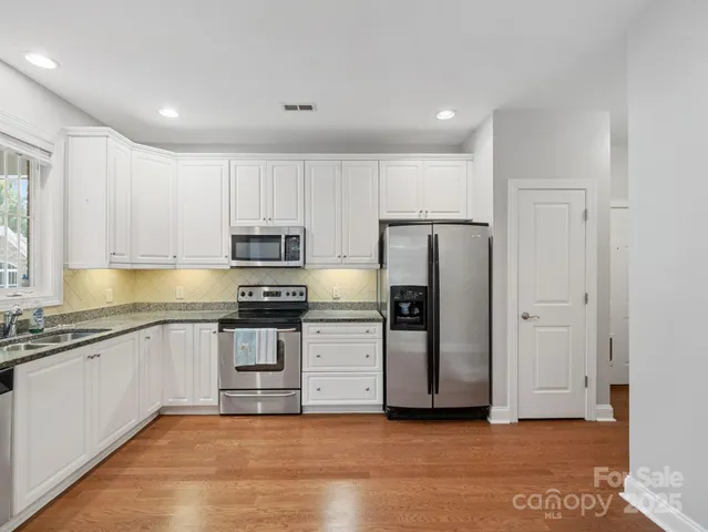 a kitchen with granite countertop white cabinets and stainless steel appliances