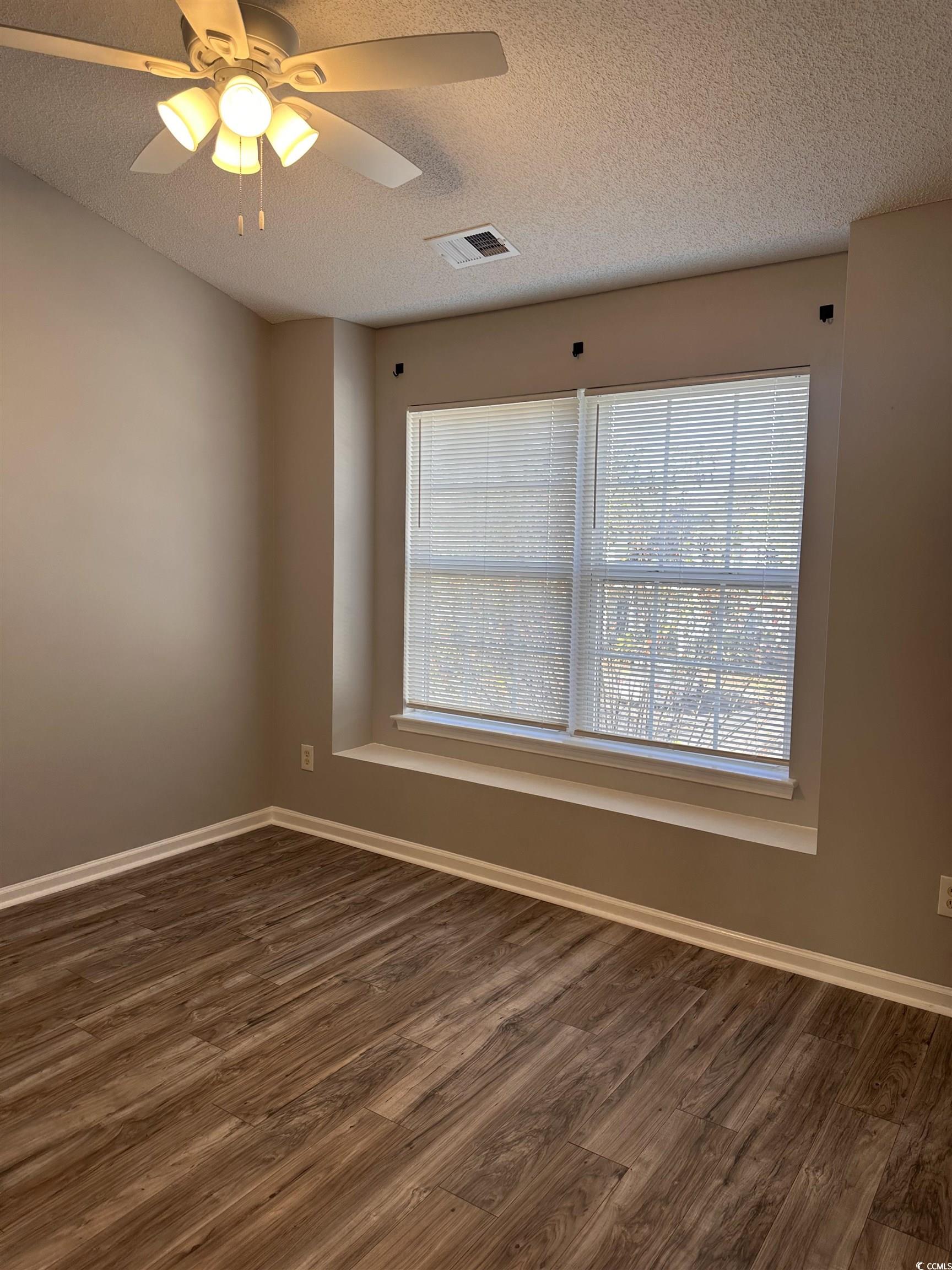 257 Seabert Road Myrtle Beach, SC 29579 - Photo 12 of 16 Spare room featuring dark wood finished floors, a textured ceiling, and a ceiling fan