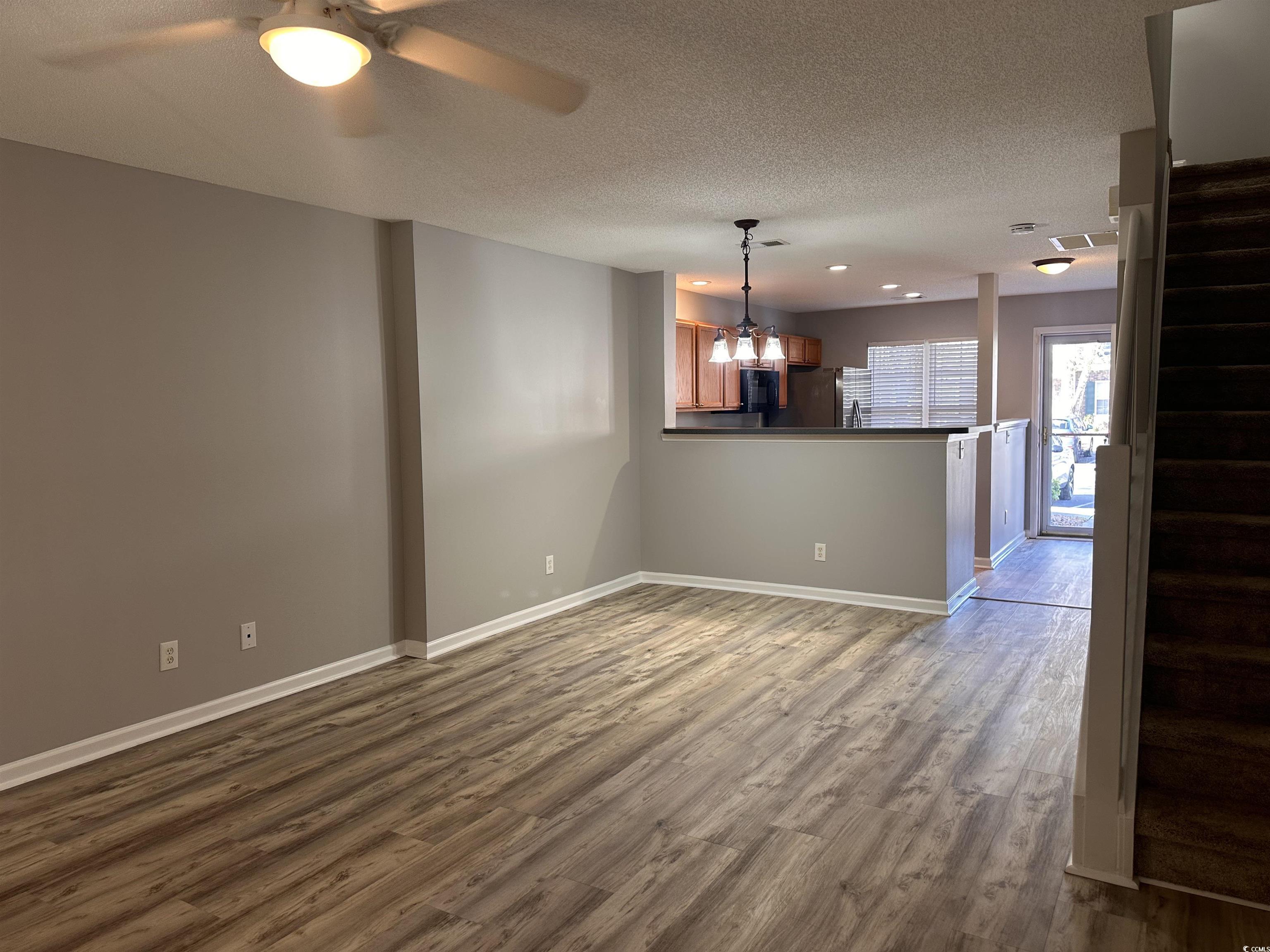 257 Seabert Road Myrtle Beach, SC 29579 - Photo 2 of 16 Unfurnished room featuring wood finished floors, stairway, a textured ceiling, and ceiling fan