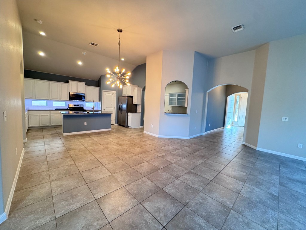16420 Pienza Drive Pflugerville, TX 78660 - Photo 26 of 26 Kitchen featuring open floor plan, dark countertops, a chandelier, decorative light fixtures, and white cabinets