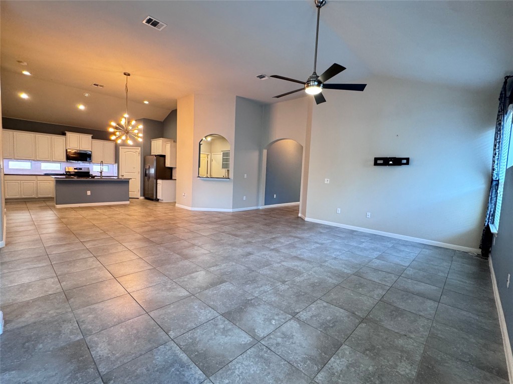 16420 Pienza Drive Pflugerville, TX 78660 - Photo 10 of 26 Unfurnished living room with high vaulted ceiling, a chandelier, a ceiling fan, arched walkways, and light tile patterned floors