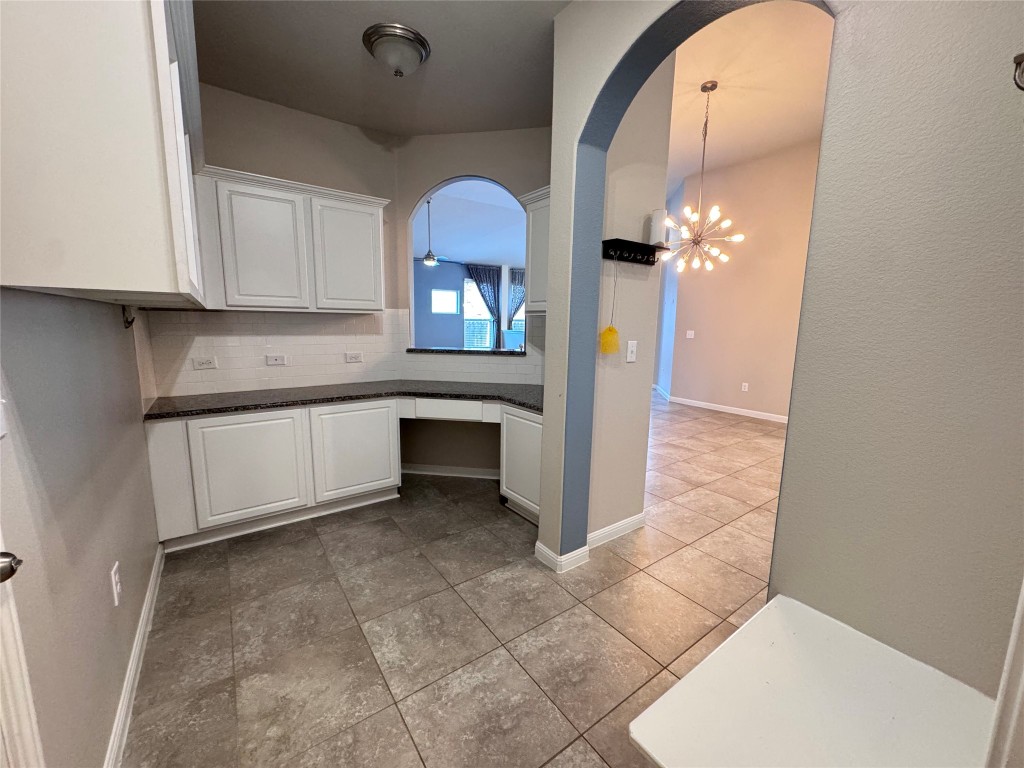 16420 Pienza Drive Pflugerville, TX 78660 - Photo 11 of 26 Kitchen featuring white cabinetry, a chandelier, tasteful backsplash, and arched walkways