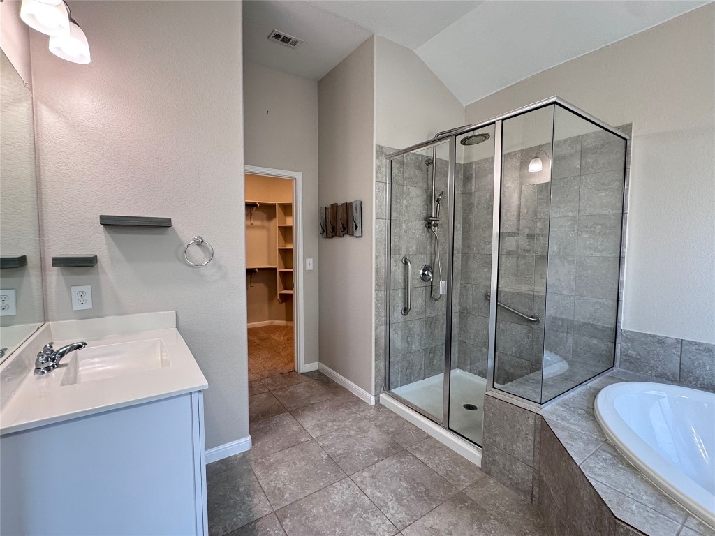 16420 Pienza Drive Pflugerville, TX 78660 - Photo 15 of 26 Full bath with a spacious closet, vanity, a bath, a shower stall, and tile patterned floors