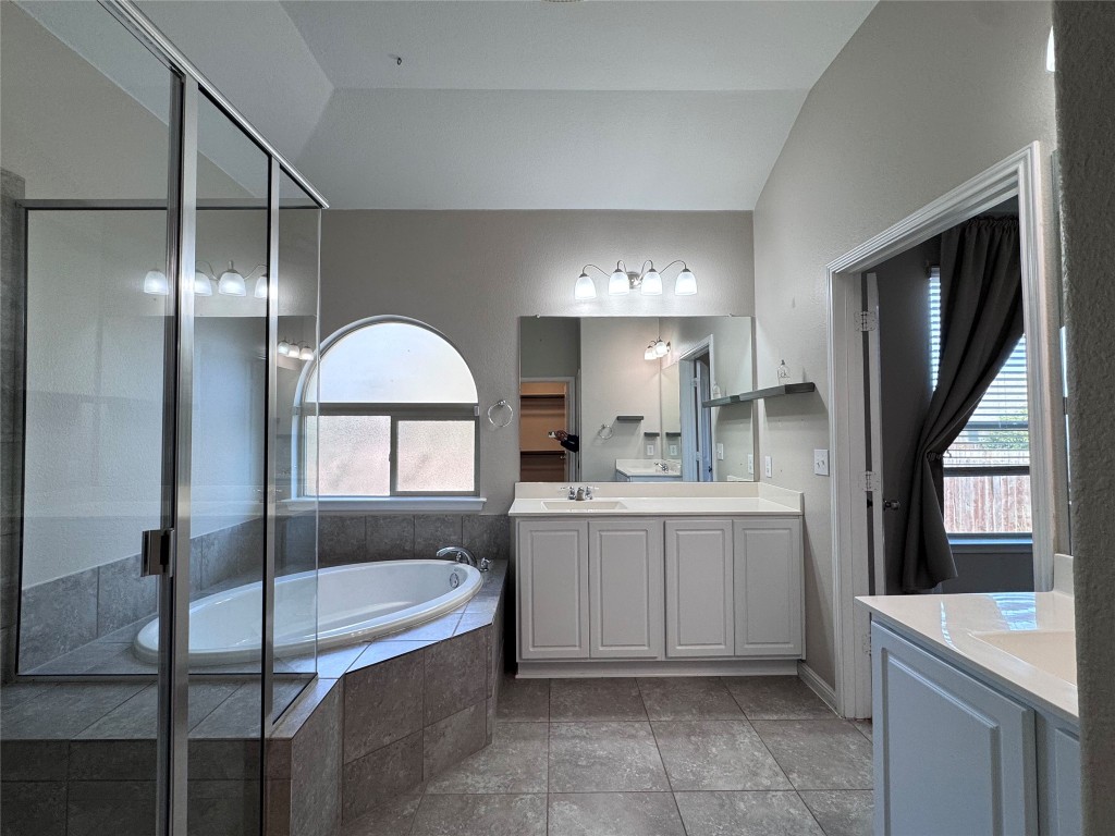 16420 Pienza Drive Pflugerville, TX 78660 - Photo 16 of 26 Bathroom with vanity, vaulted ceiling, a garden tub, a shower stall, and dark tile patterned flooring