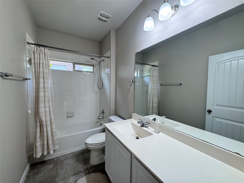 16420 Pienza Drive Pflugerville, TX 78660 - Photo 21 of 26 Full bathroom with shower / tub combo with curtain, vanity, and dark tile patterned flooring