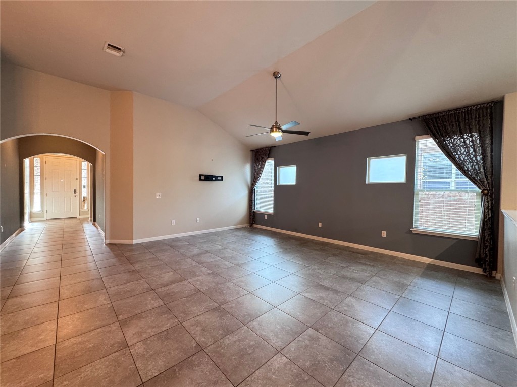 16420 Pienza Drive Pflugerville, TX 78660 - Photo 4 of 26 Empty room with arched walkways, vaulted ceiling, plenty of natural light, light tile patterned floors, and a ceiling fan