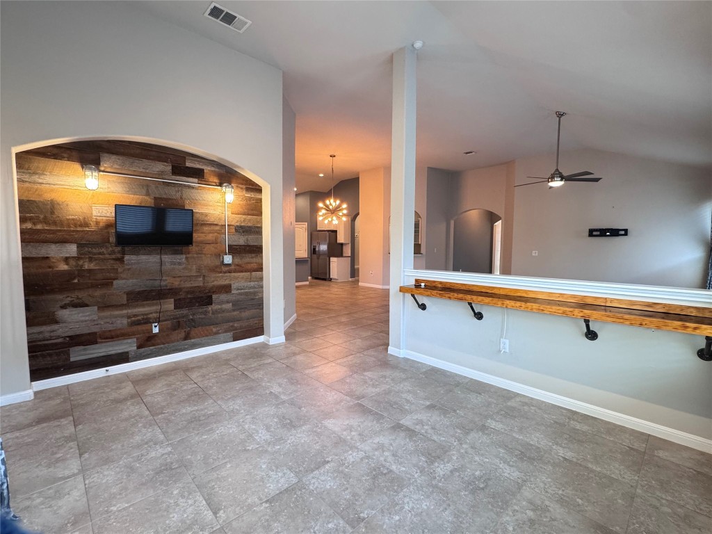 16420 Pienza Drive Pflugerville, TX 78660 - Photo 6 of 26 Kitchen with wood walls, arched walkways, a chandelier, black fridge, and vaulted ceiling