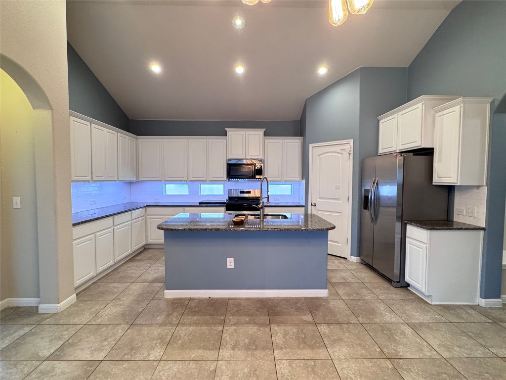 16420 Pienza Drive Pflugerville, TX 78660 - Photo 7 of 26 Kitchen with white cabinetry, dark stone countertops, arched walkways, a kitchen island with sink, and recessed lighting