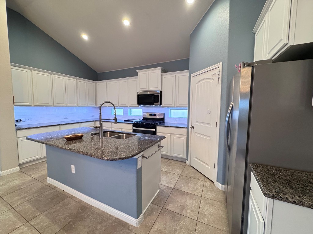 16420 Pienza Drive Pflugerville, TX 78660 - Photo 9 of 26 Kitchen featuring appliances with stainless steel finishes, dark stone counters, white cabinets, a kitchen island with sink, and recessed lighting